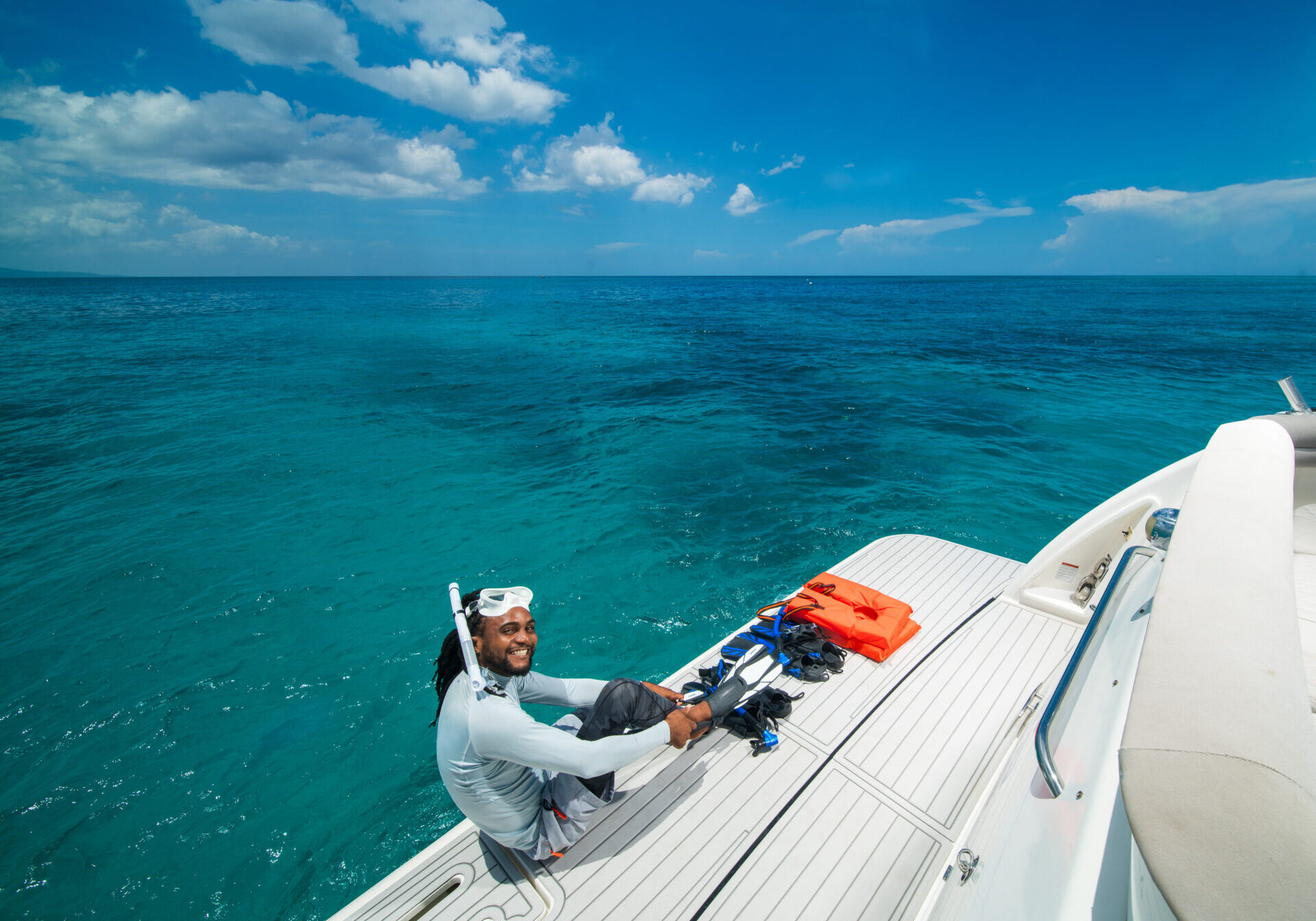 A man sitting on the side of a boat in the ocean.
